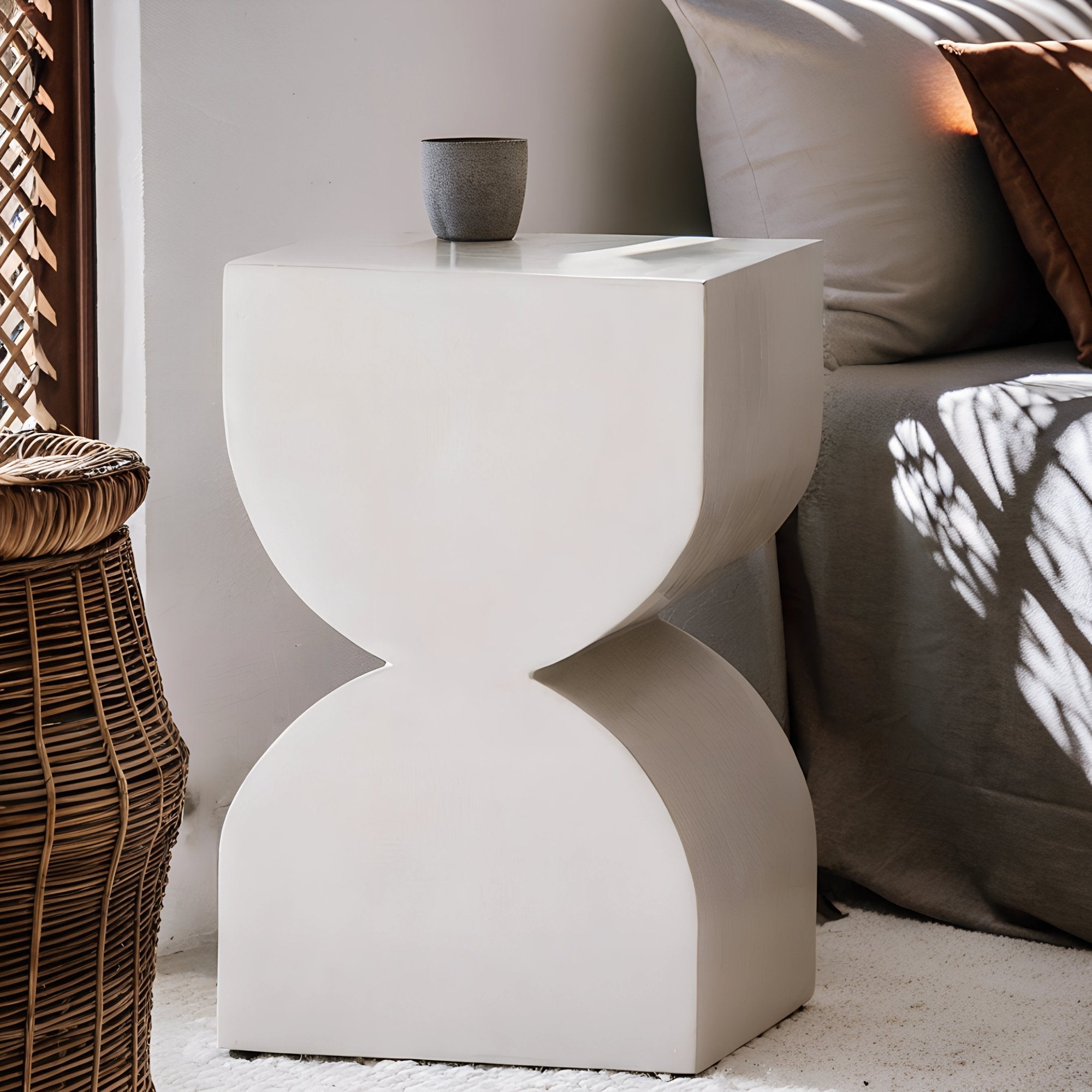 Table d’appoint en béton ciré aux lignes épurées, apportant une touche industrielle et contemporaine, mise en scène avec une bougie et une tasse en céramique.