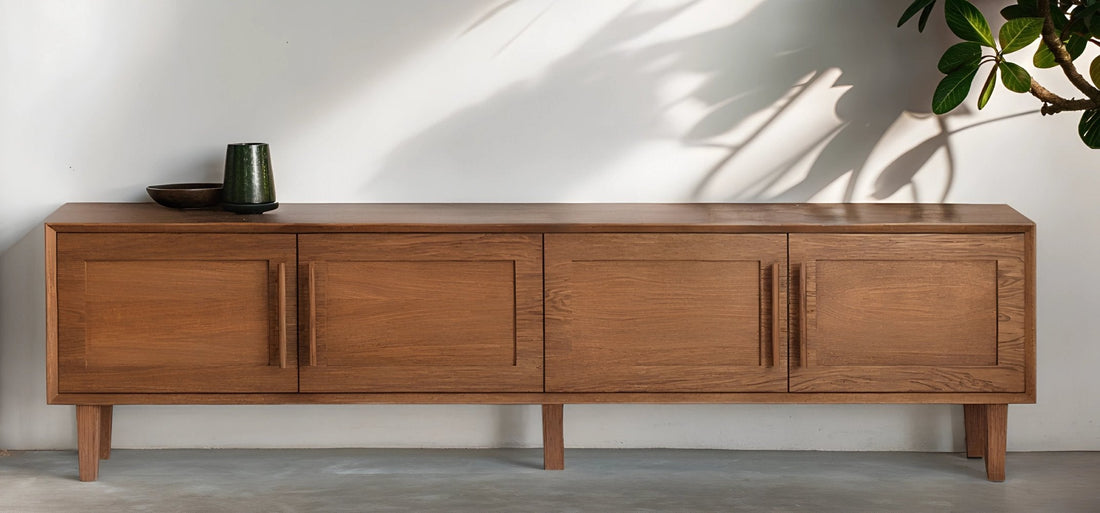 Buffet en chêne teinté au design épuré, sublimé par des plantes en pot et une décoration naturelle dans un intérieur lumineux.