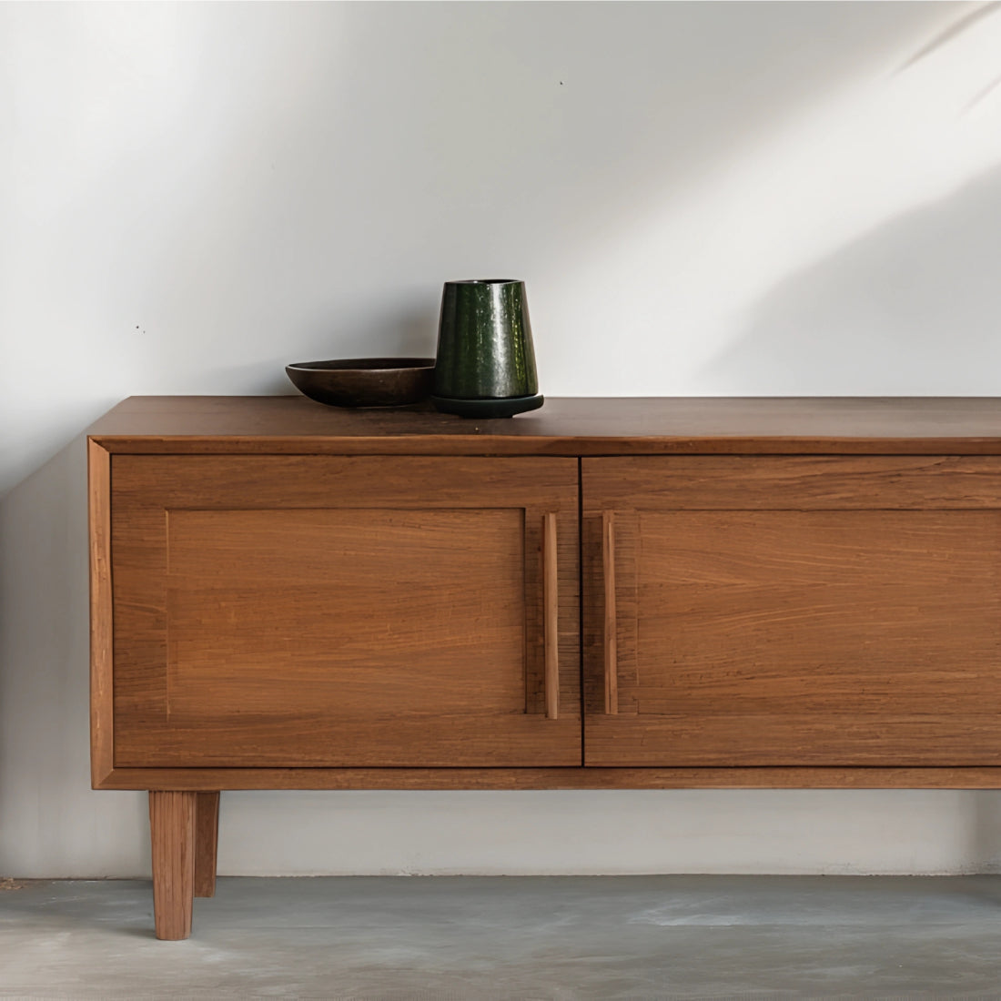 Buffet en chêne teinté au design épuré, sublimé par des plantes en pot et une décoration naturelle dans un intérieur lumineux.