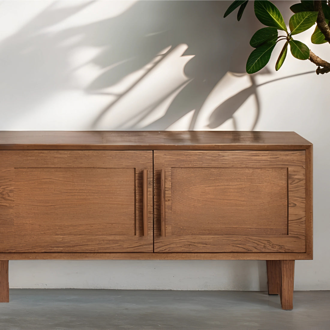 Buffet en chêne teinté au design épuré, sublimé par des plantes en pot et une décoration naturelle dans un intérieur lumineux.