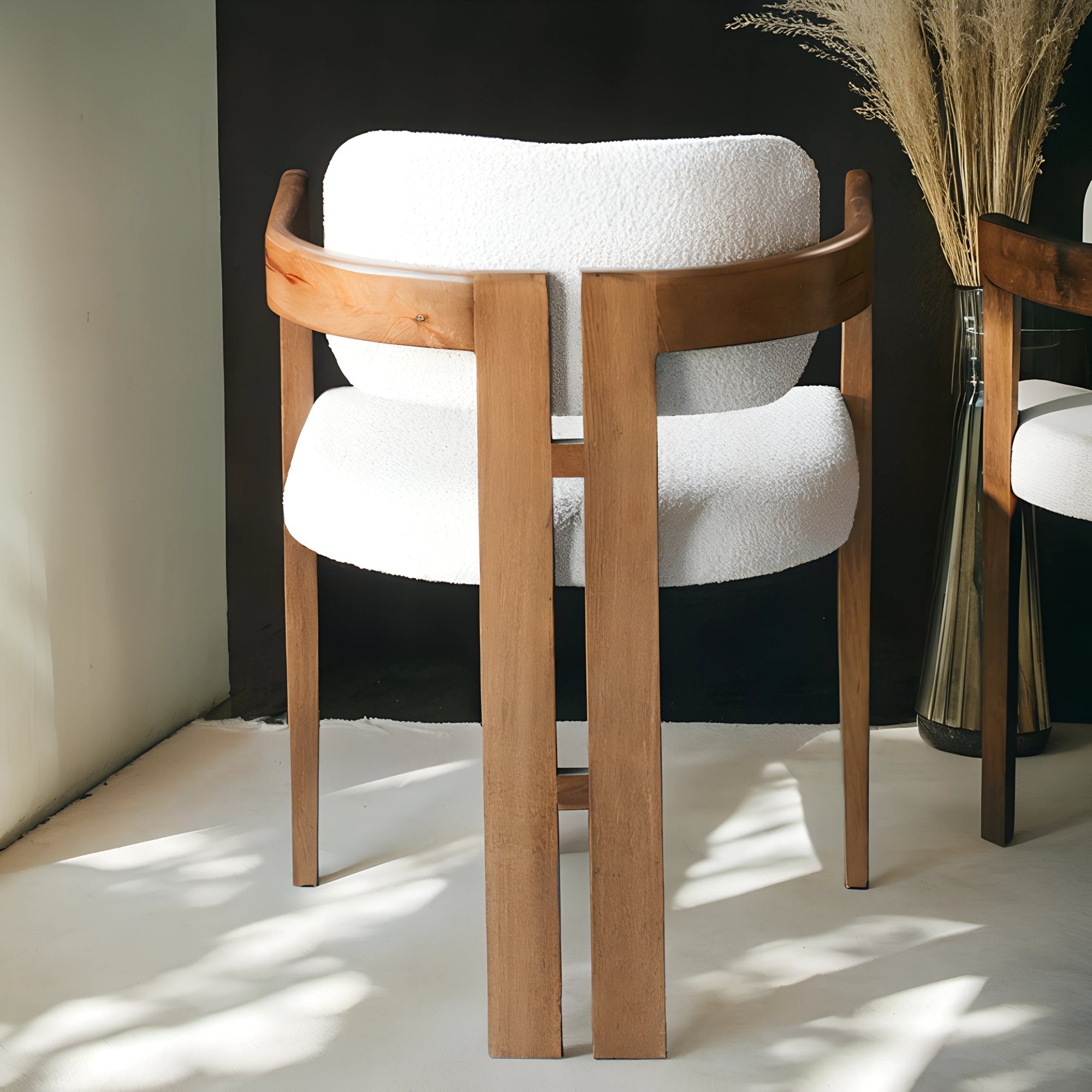 Chaise en bois avec assise en tissu bouclette, alliant chaleur naturelle et douceur texturée pour un confort enveloppant et un design élégant. 