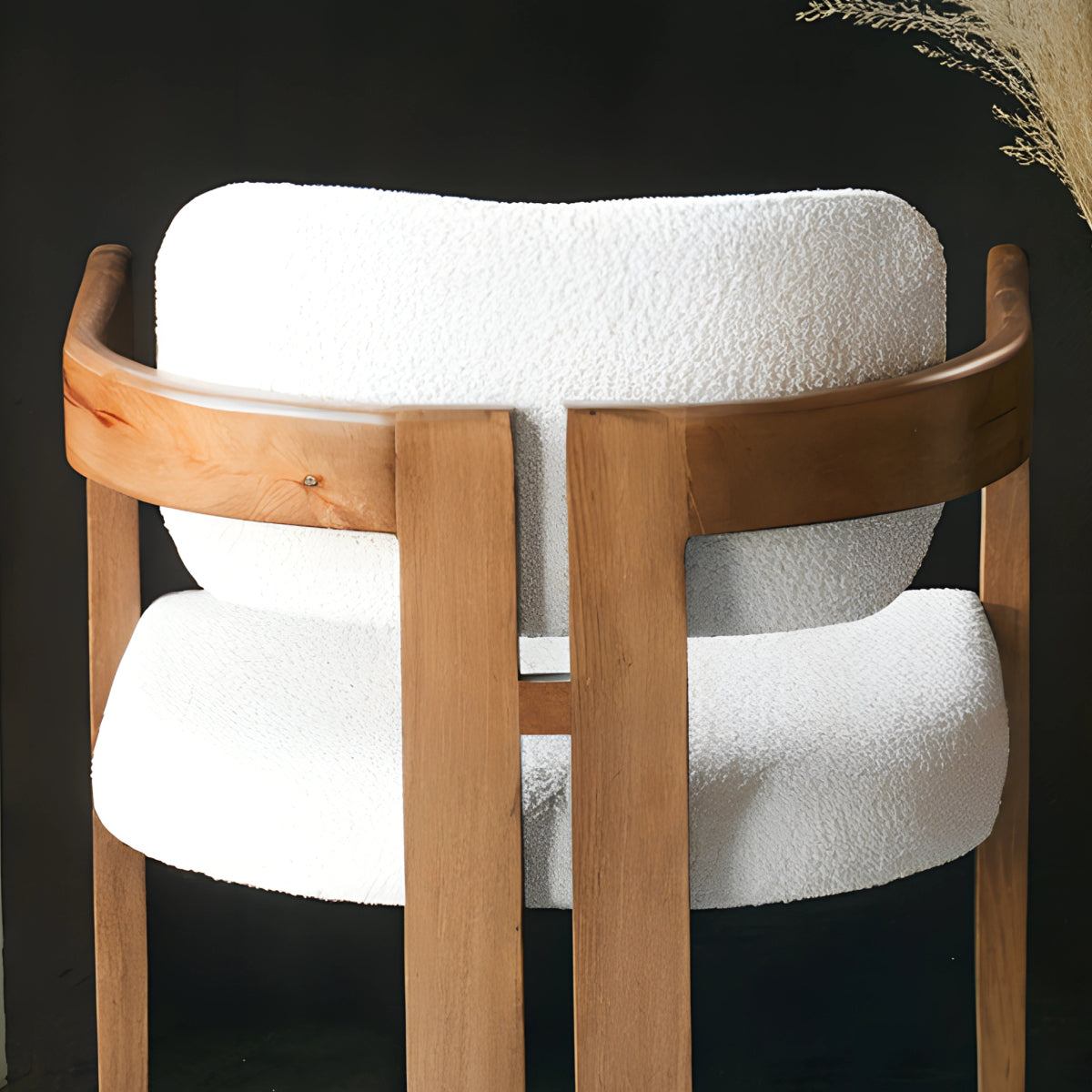 Chaise en bois avec assise en tissu bouclette, alliant chaleur naturelle et douceur texturée pour un confort enveloppant et un design élégant.