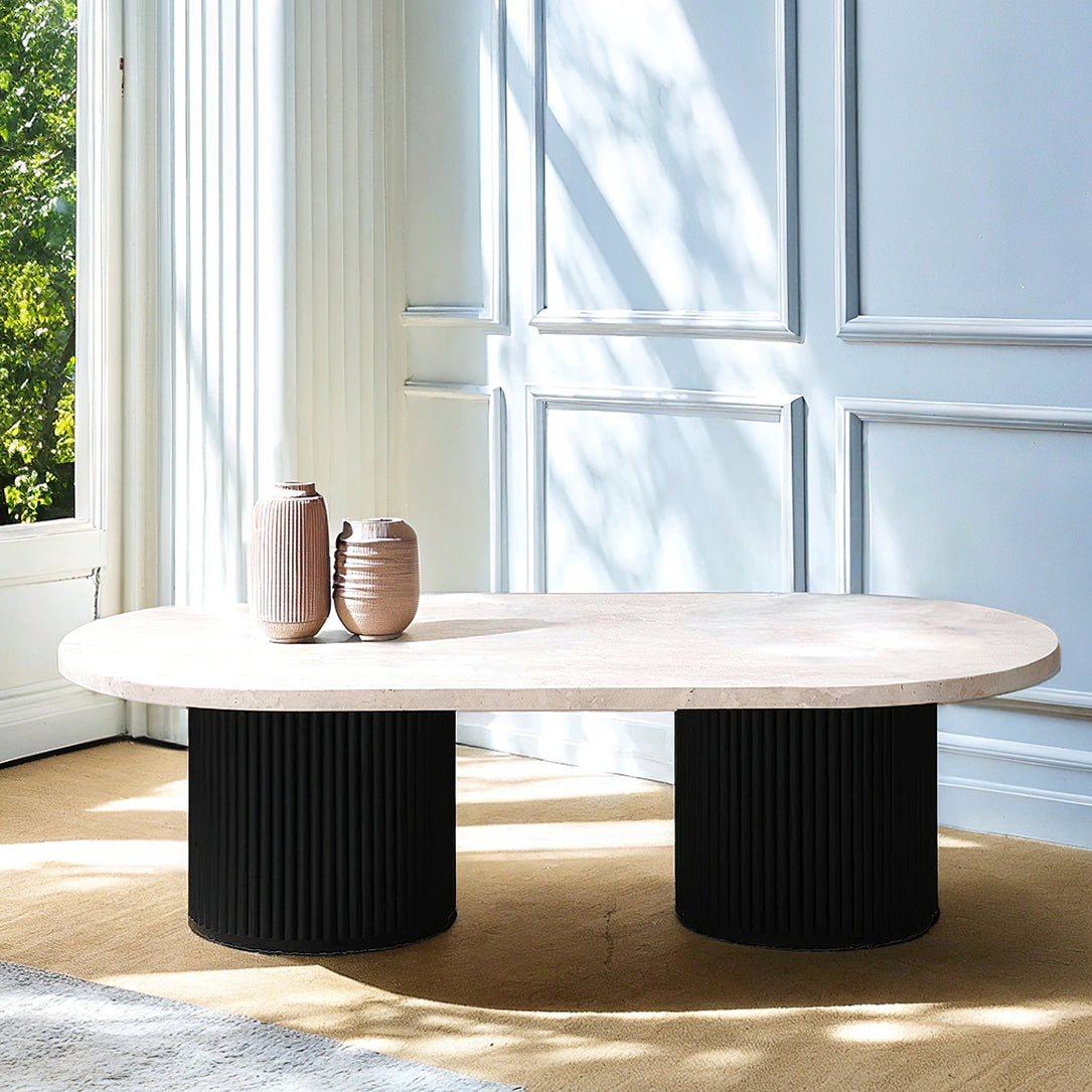 Table basse en travertin et bois noir, contrastant élégance minérale et profondeur boisée, agrémentée de livres et d’objets design.