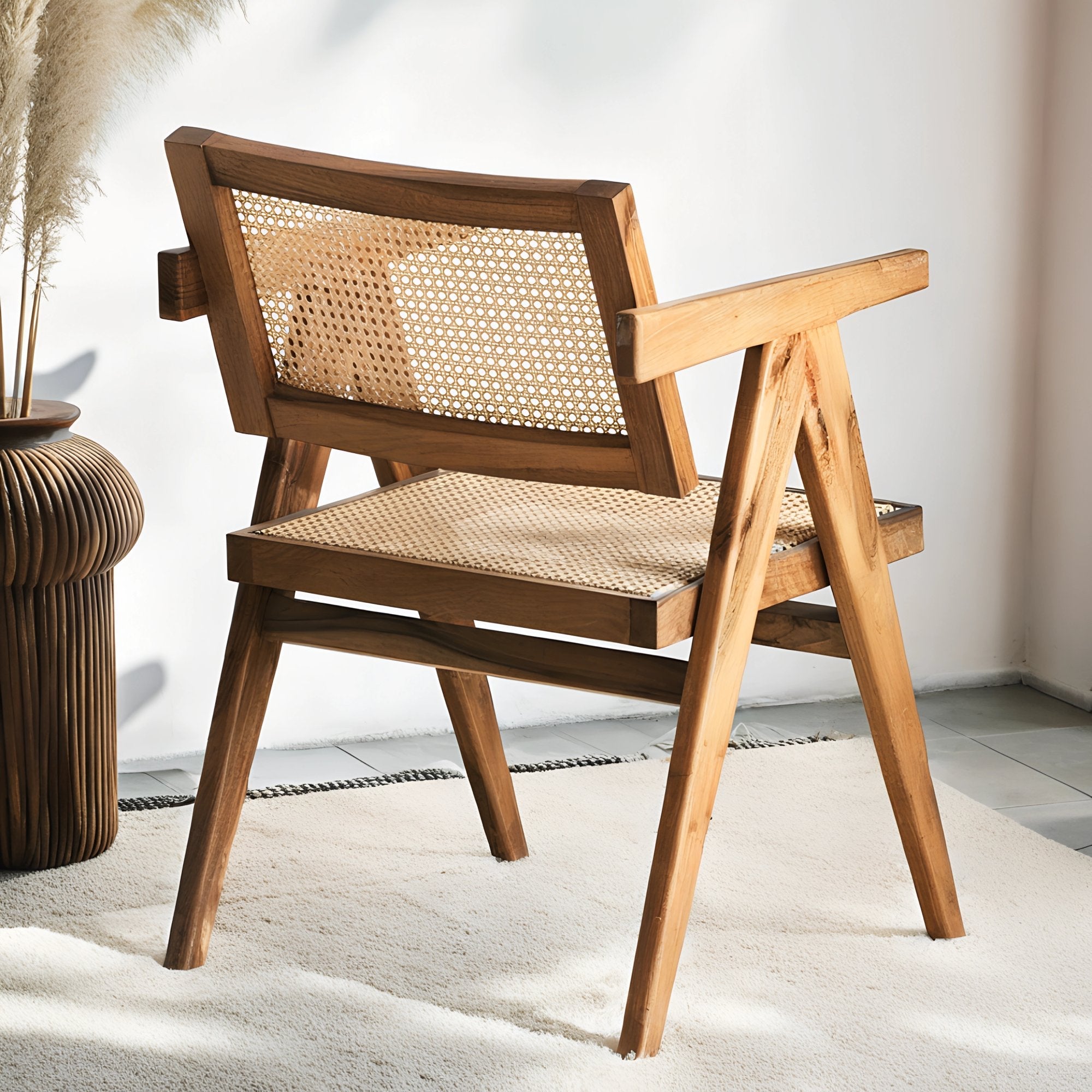 Fauteuil en noyer avec assise et dossier en cannage, au design raffiné et intemporel, accompagné d’un plaid en lin et d’une table d’appoint en pierre.