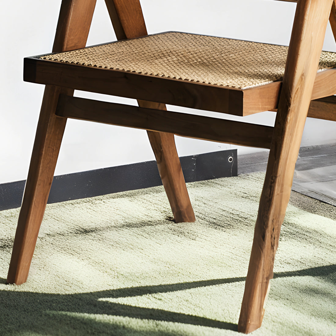 Fauteuil en noyer avec assise et dossier en cannage, au design raffiné et intemporel, accompagné d’un plaid en lin et d’une table d’appoint en pierre.