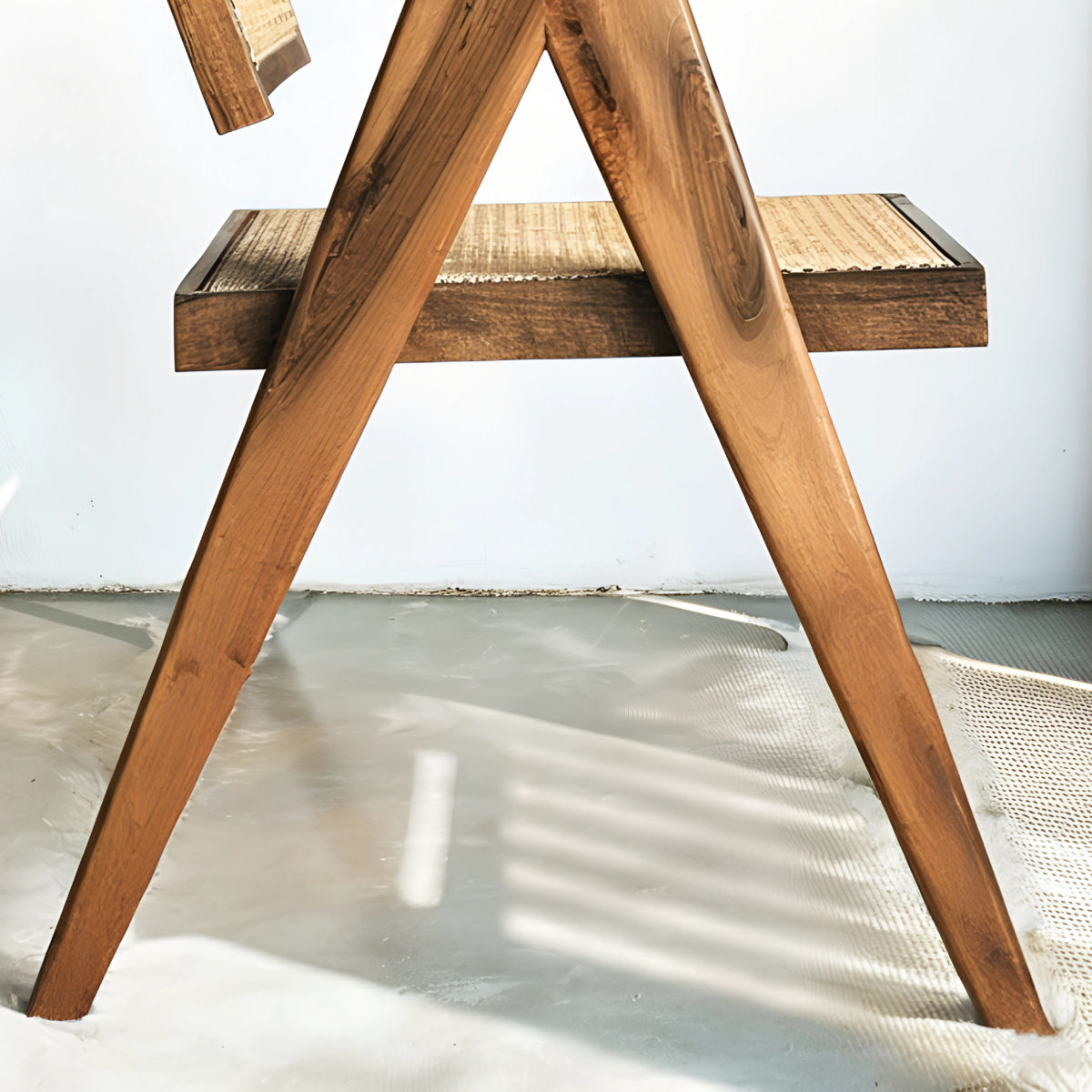 Fauteuil en noyer avec assise et dossier en cannage, au design raffiné et intemporel, accompagné d’un plaid en lin et d’une table d’appoint en pierre.