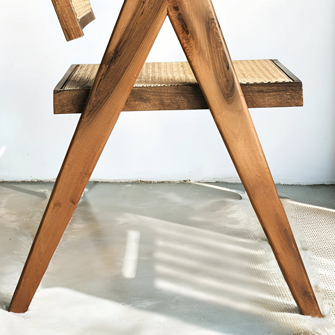 Fauteuil en noyer avec assise et dossier en cannage, au design raffiné et intemporel, accompagné d’un plaid en lin et d’une table d’appoint en pierre.