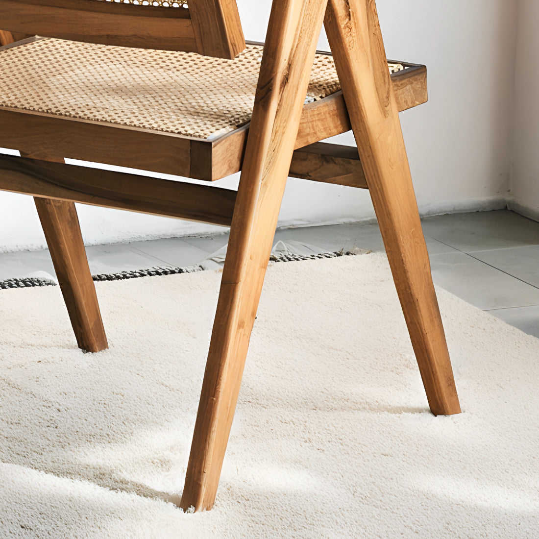 Fauteuil en noyer avec assise et dossier en cannage, au design raffiné et intemporel, accompagné d’un plaid en lin et d’une table d’appoint en pierre.