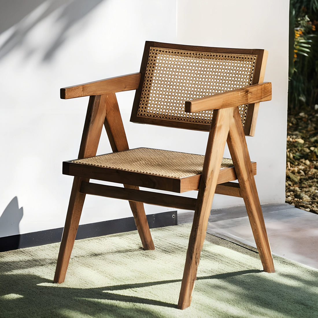 Fauteuil en noyer avec assise et dossier en cannage, au design raffiné et intemporel, accompagné d’un plaid en lin et d’une table d’appoint en pierre.