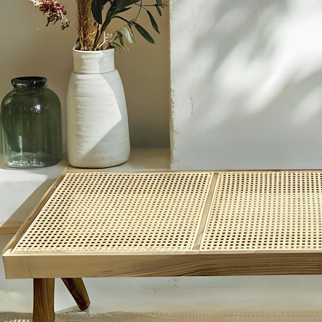 Banc en noyer avec assise en rotin tressé, alliant élégance et authenticité, disposé dans un intérieur chaleureux avec tapis en laine et coussins en lin.