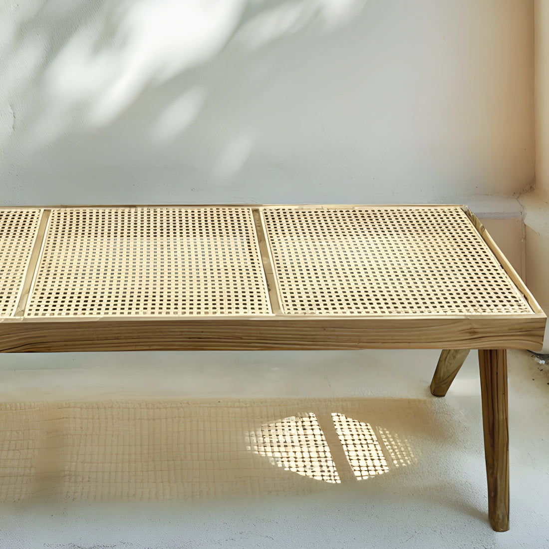 Banc en noyer avec assise en rotin tressé, alliant élégance et authenticité, disposé dans un intérieur chaleureux avec tapis en laine et coussins en lin.