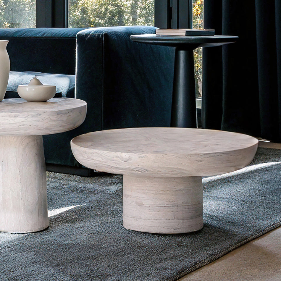 Table basse en travertin massif, au design brut et sophistiqué, mise en scène avec des bougies et une sculpture décorative.