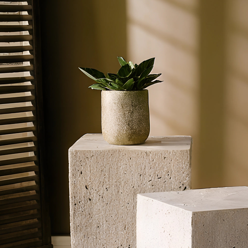 Colonne en travertin aux nuances beiges et veinage naturel, utilisée comme table d’appoint ou piédestal décoratif, disposée dans un intérieur épuré avec vase en céramique et luminaire design.