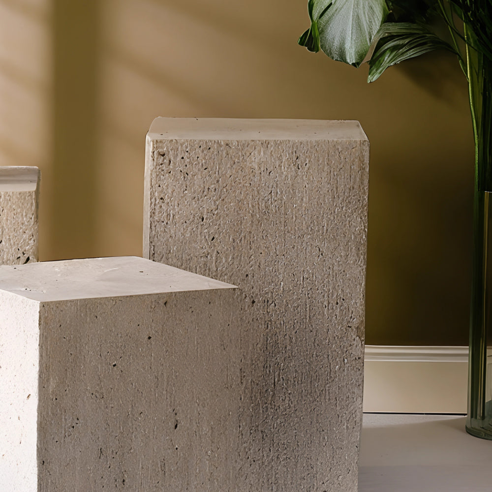 Colonne en travertin aux nuances beiges et veinage naturel, utilisée comme table d’appoint ou piédestal décoratif, disposée dans un intérieur épuré avec vase en céramique et luminaire design.