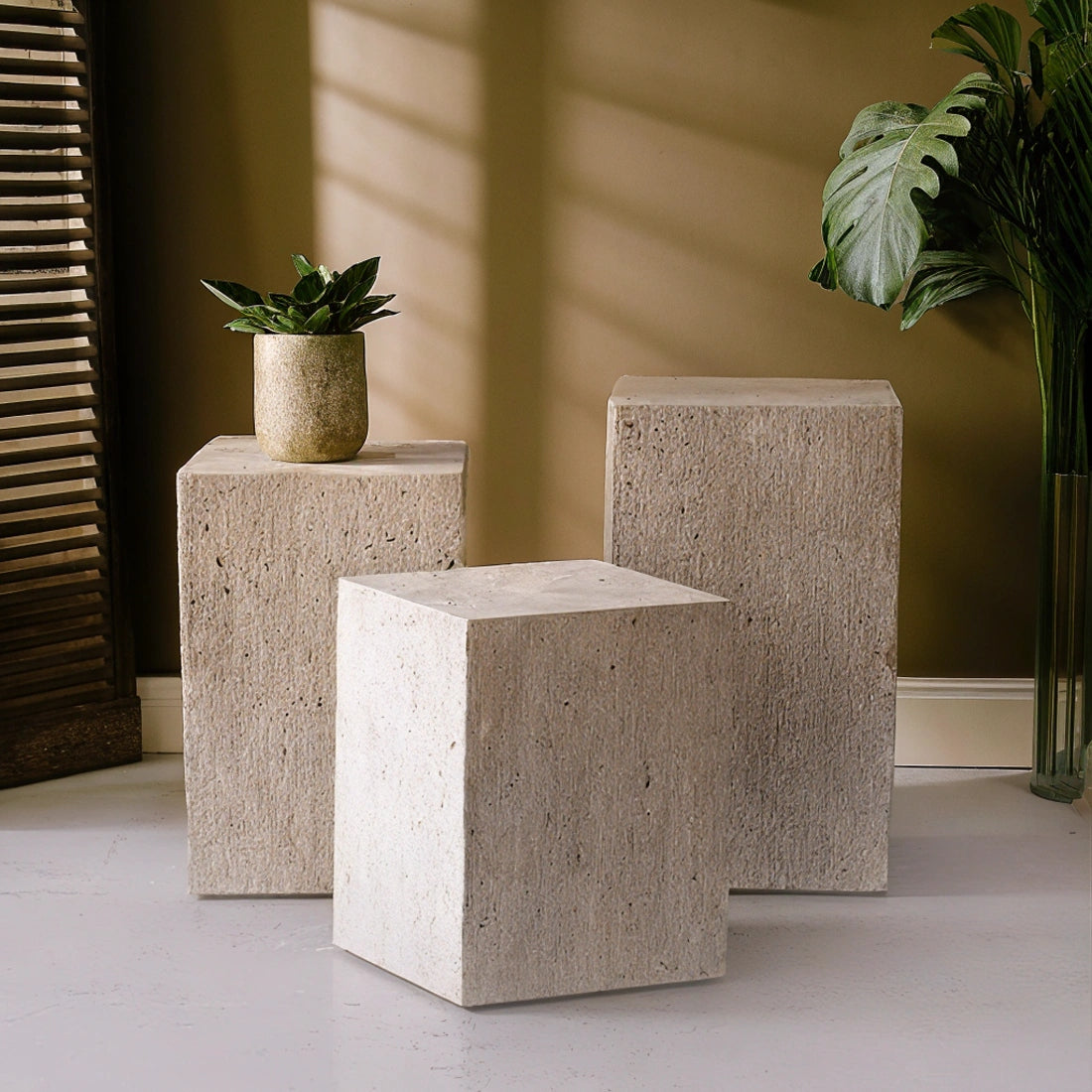 Colonne en travertin aux nuances beiges et veinage naturel, utilisée comme table d’appoint ou piédestal décoratif, disposée dans un intérieur épuré avec vase en céramique et luminaire design.